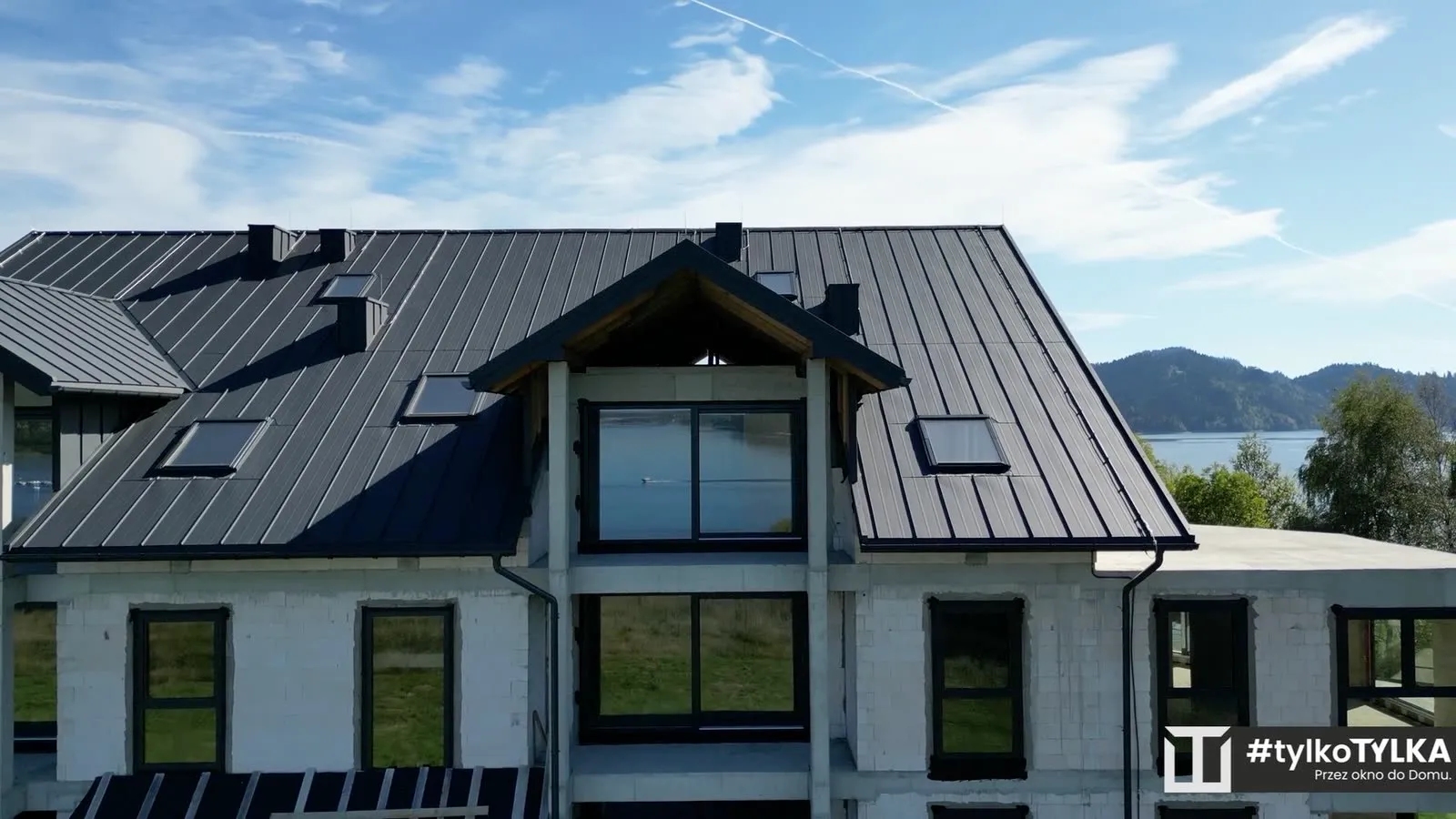 Dach apartamentowca z lotu ptaka, jezioro odbite w szybach