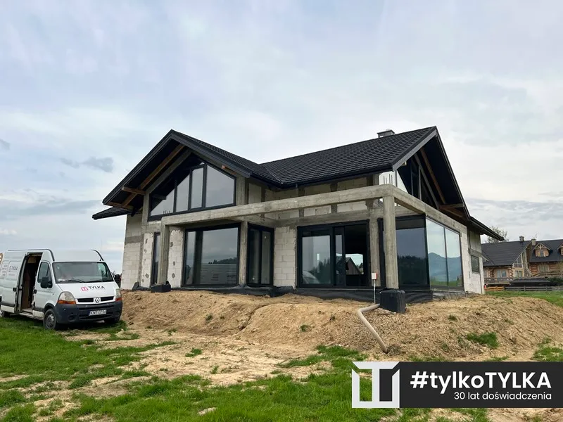 Duże przeszklenie z czarną stolarką i widokiem na Tatry
