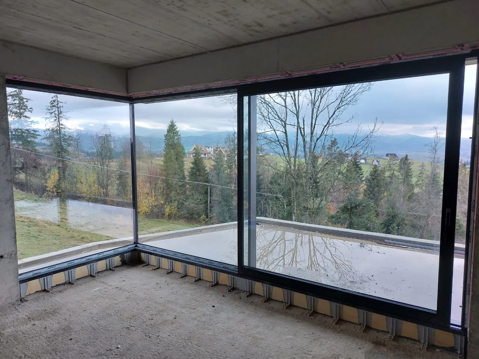 Narożne przeszklenie aluminiowe osadzone w warstwie ocieplenia, widok z wnętrza na Tatry